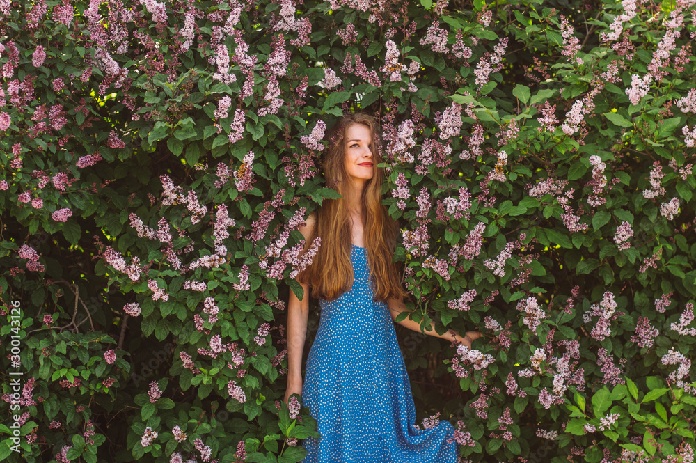 Portrait of smiling looking up girl with blond hair and blue dress among lilac Portrait of smiling looking up girl with blond hair and blue dress among lilac