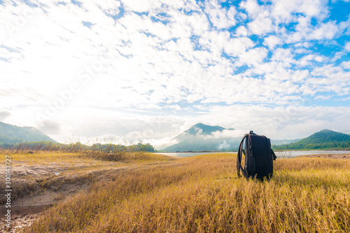 Black backpack on the yellow grass background with mountain view photo