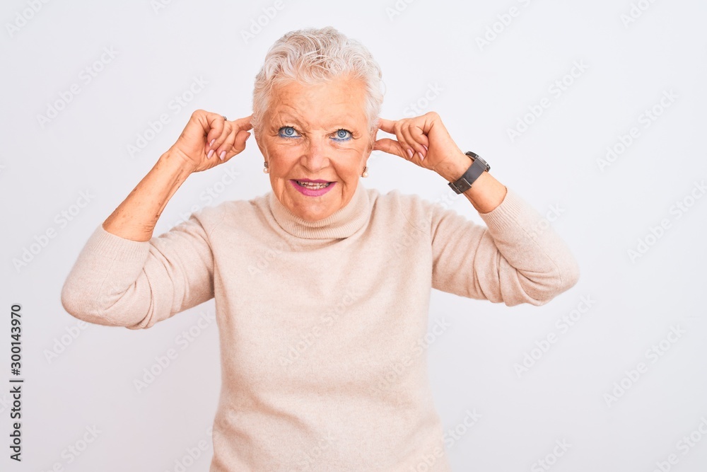Senior grey-haired woman wearing turtleneck sweater standing over isolated white background Smiling pulling ears with fingers, funny gesture. Audition problem Senior grey-haired woman wearing turtleneck sweater standing over isolated white background Smiling pulling ears with fingers, funny gesture. Audition problem