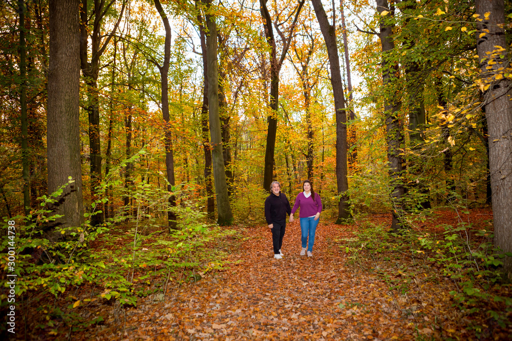 Couple walking in the forest during a late autumn afternoon.