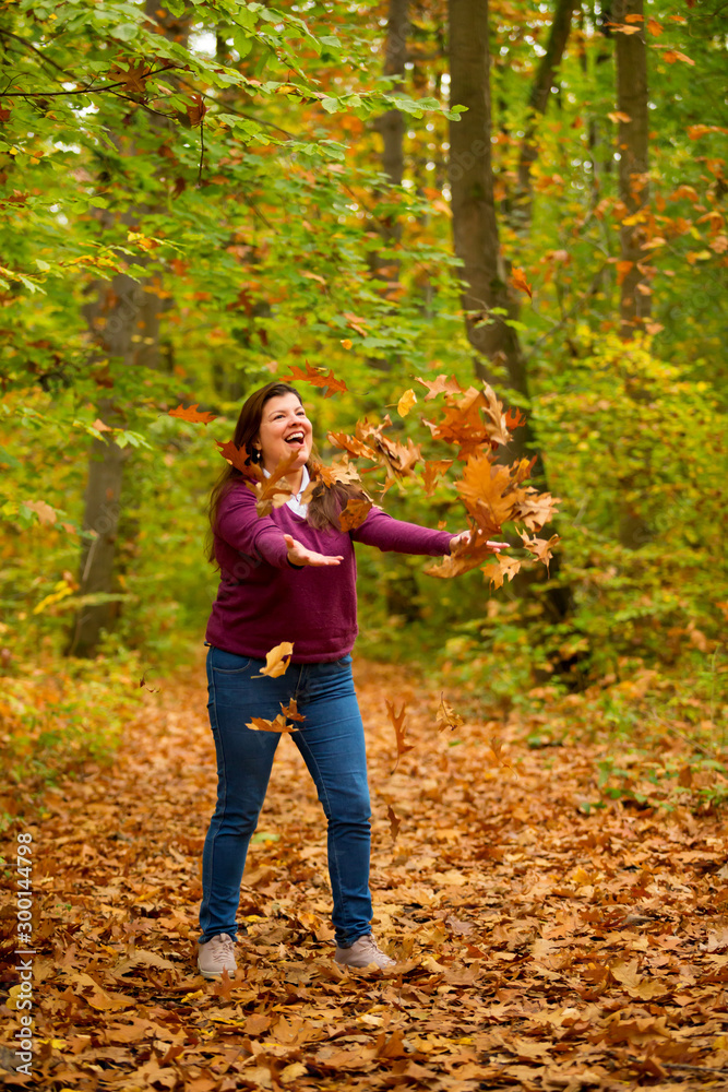Lady playful with colorful autumn leaves throwing up in the air the fallen leaves. Lady playful with colorful autumn leaves throwing up in the air the fallen leaves.