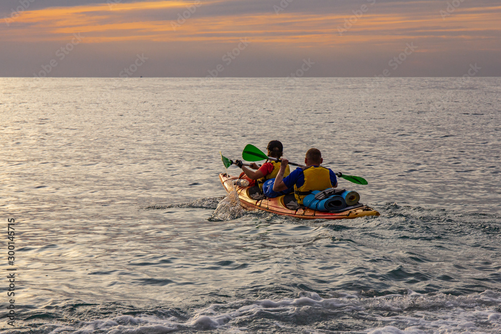 athletes kayakers (man and woman) go on a kayak trip on the Bay of Black sea to meet the beautiful dawn. Amazing views. Perfect activity for holidays. The Peninsula of the Crimea, Russia, Ukraine.