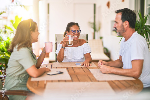Beautiful family sitting on terrace drinking cup of coffee speaking and smiling