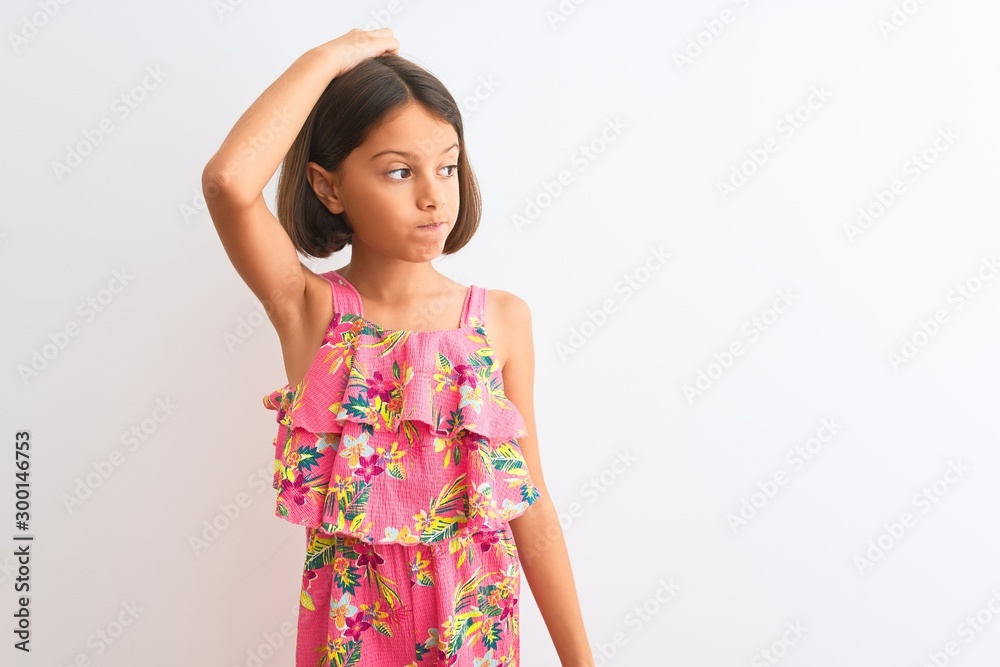 Young beautiful child girl wearing pink floral dress standing over isolated white background confuse and wonder about question. Uncertain with doubt, thinking with hand on head. Pensive concept. Young beautiful child girl wearing pink floral dress standing over isolated white background confuse and wonder about question. Uncertain with doubt, thinking with hand on head. Pensive concept.