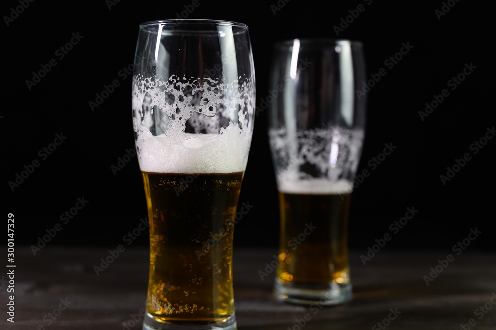 Photo of beer in two glasses. Thick foam and a nice color drink on a black background. Photo of beer in two glasses. Thick foam and a nice color drink on a black background.