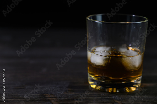 Photo of whiskey in a glass with ice. Real ice and a pleasant color of the drink on a black background.