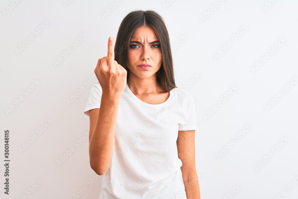 Young beautiful woman wearing casual t-shirt standing over isolated white background Showing middle finger, impolite and rude fuck off expression Young beautiful woman wearing casual t-shirt standing over isolated white background Showing middle finger, impolite and rude fuck off expression