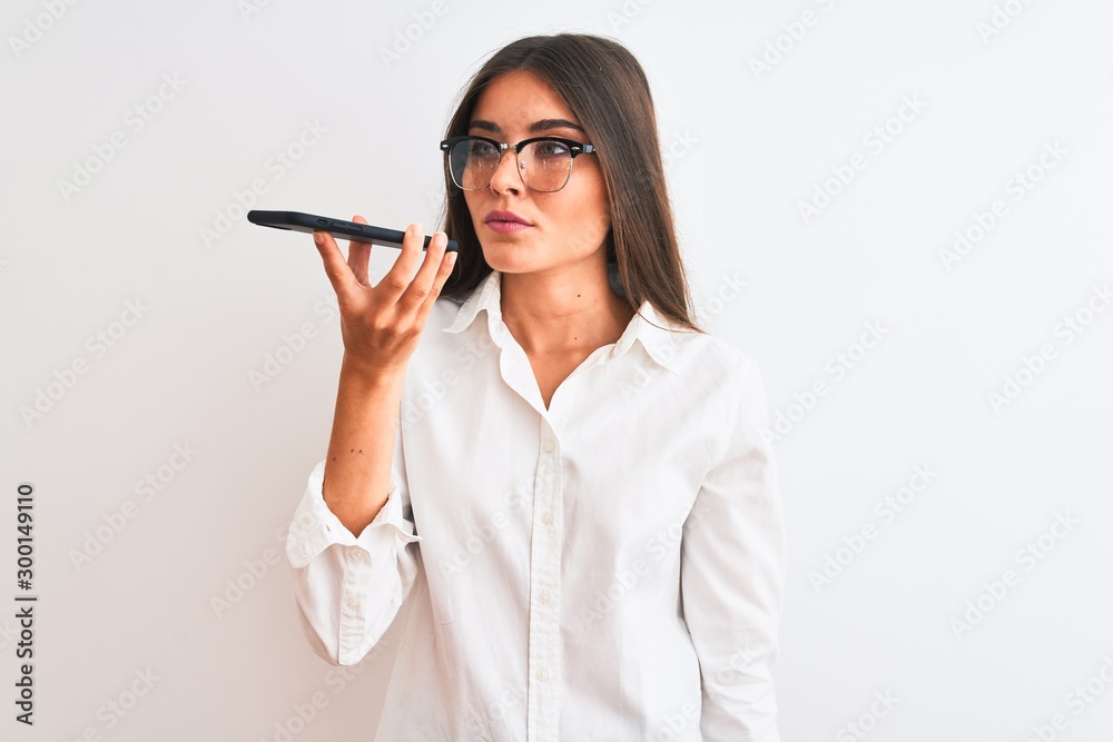 Woman wearing glasses sending message on smartphone over isolated white background with a confident expression on smart face thinking serious Woman wearing glasses sending message on smartphone over isolated white background with a confident expression on smart face thinking serious