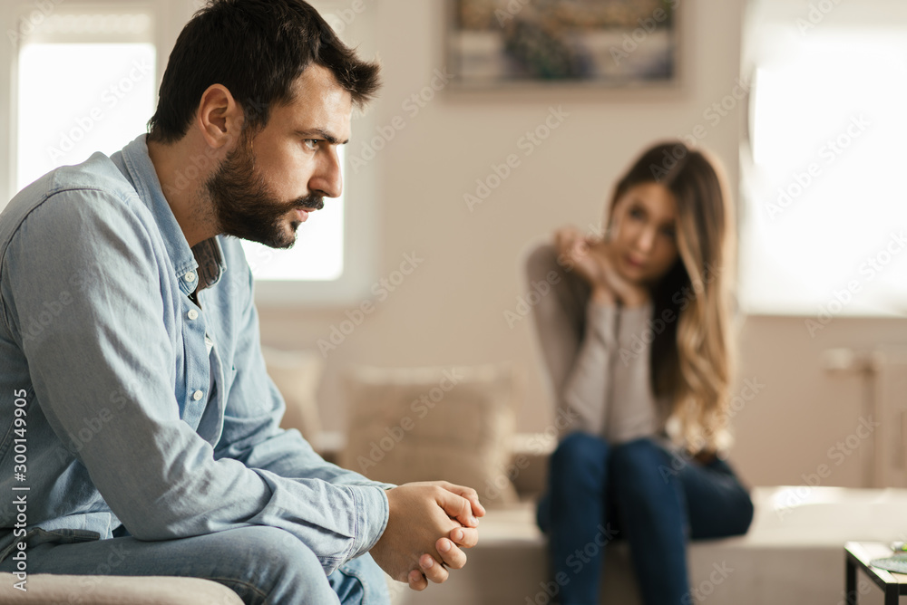 Young man feeling sad after arguing with his girlfriend on sofa at home Young man feeling sad after arguing with his girlfriend on sofa at home