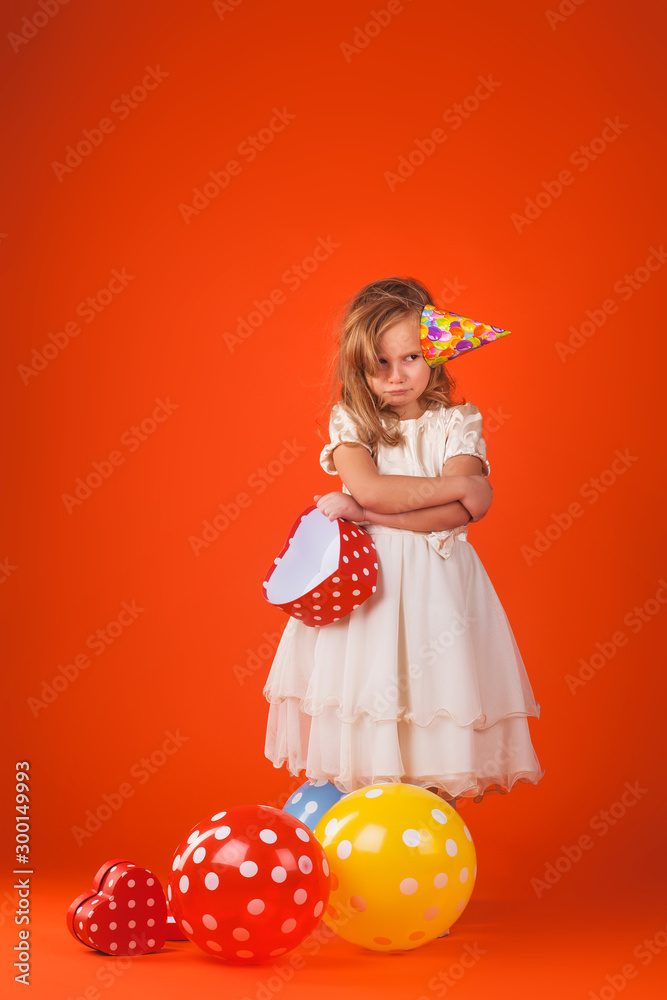 girl with gifts and balloons on an orange background. Studio portrait photos