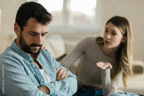 Angry man doesn't pay attention to his girlfriend who is asking for his forgiveness