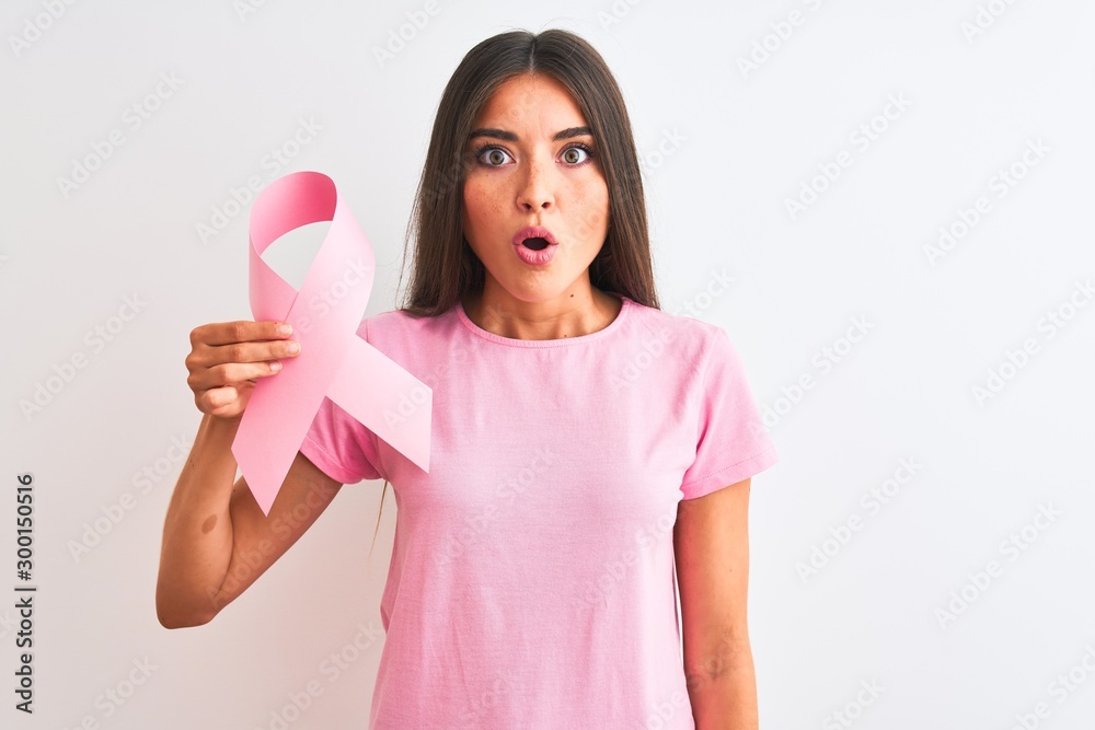 Young beautiful woman holding cancer ribbon standing over isolated white background scared in shock with a surprise face, afraid and excited with fear expression Young beautiful woman holding cancer ribbon standing over isolated white background scared in shock with a surprise face, afraid and excited with fear expression