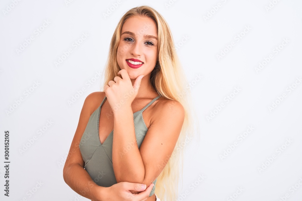 Young beautiful woman wearing casual green t-shirt standing over isolated white background looking confident at the camera smiling with crossed arms and hand raised on chin. Thinking positive. Young beautiful woman wearing casual green t-shirt standing over isolated white background looking confident at the camera smiling with crossed arms and hand raised on chin. Thinking positive.