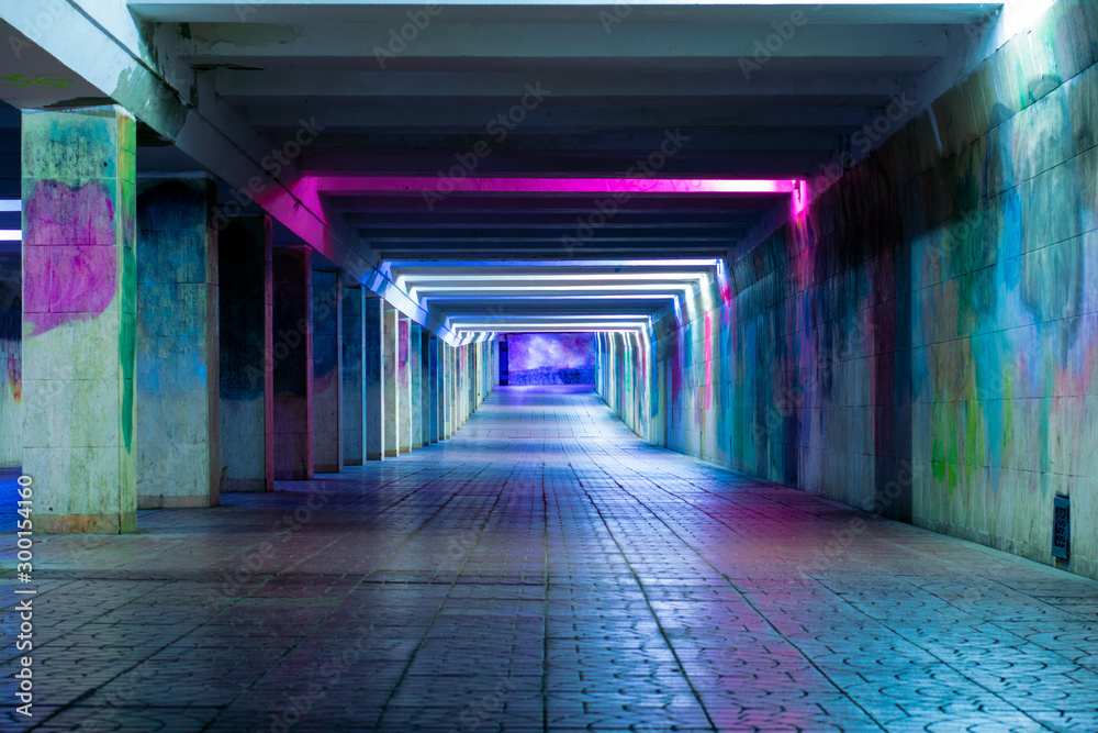 Long luminous tunnel with colorful walls. Underpass with neon lamps