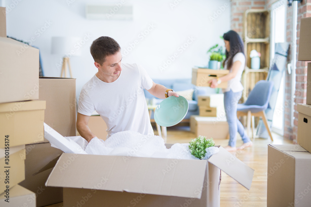 Young beautiful couple open cardboard boxes to order new home Young beautiful couple open cardboard boxes to order new home