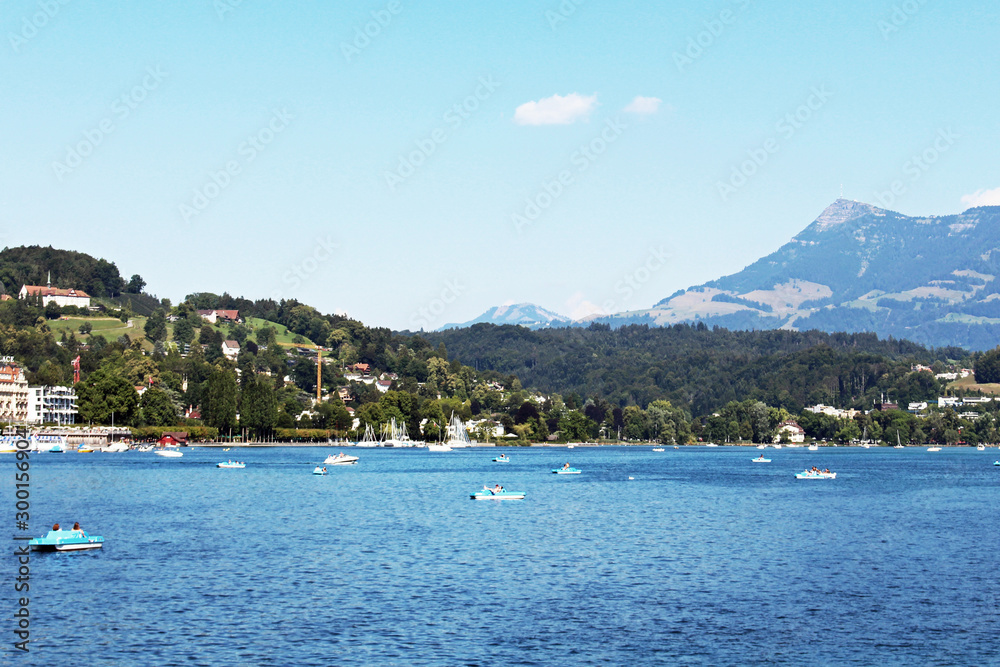 Boats in harbor in Lucerne Switzerland city with mountain rigi in background blue sky and water