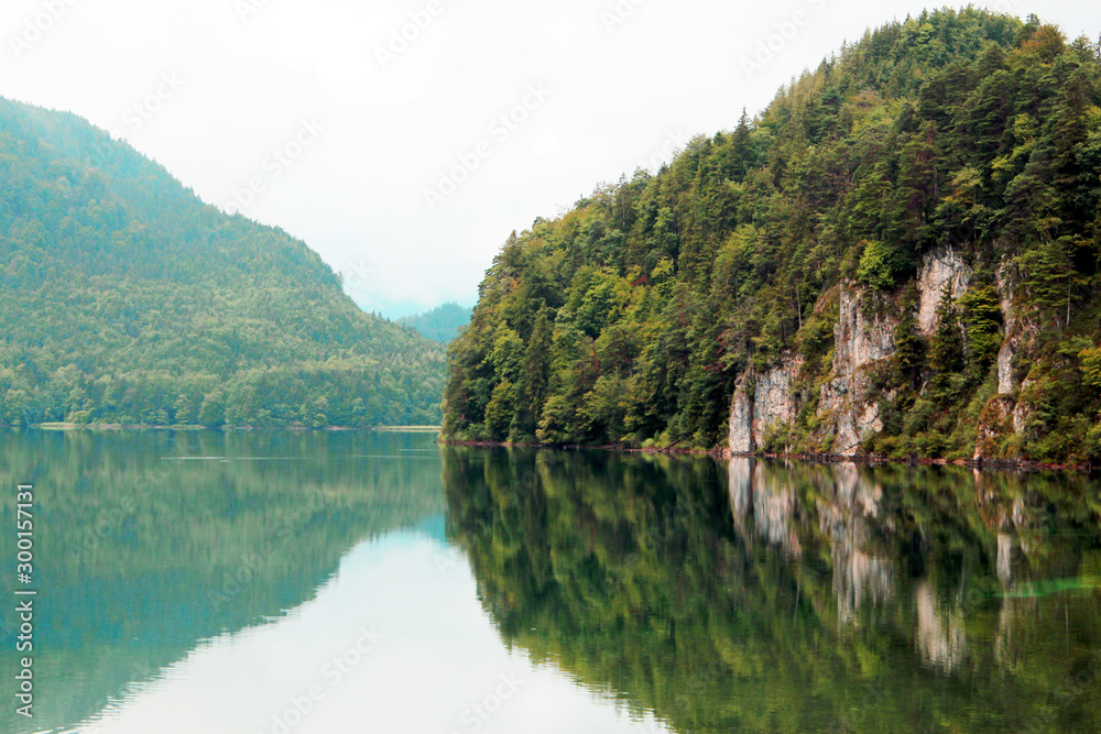 Green cliffs on lake with reflection of mountains in background in Fussen Bavaria Germany