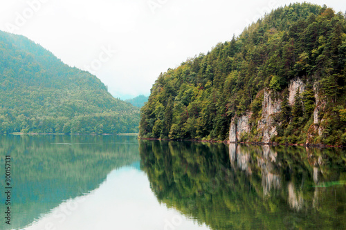 Green cliffs on lake with reflection of mountains in background in Fussen Bavaria Germany