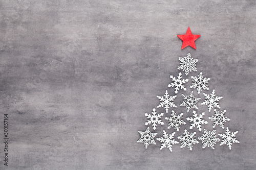 Christmas tree made from white snow flake decoration on gray background. Flat lay, top view