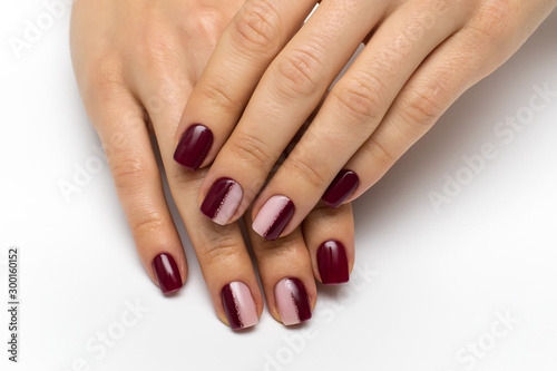 Hands close up. Burgundy beige manicure with a pink shiny strip on short square nails. Half a manicure. Color manicure.
