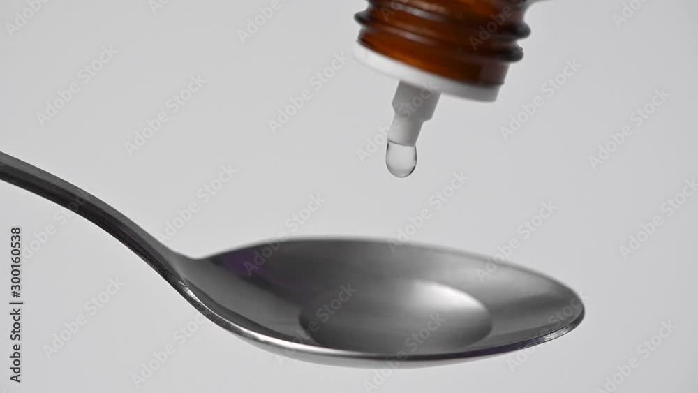 Slow motion Close up of hand in medical glove dropping liquid with a dropper bottle on a teaspoon