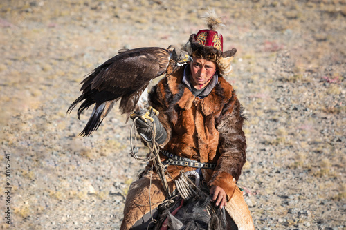 Portrait of a traditional kazakh eagle hunter with his golden eagle on horseback. Ulgii, Mongolia.