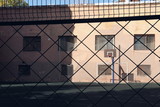View through a fence on a basketball hoop lit by the autumn sun on an empty playground