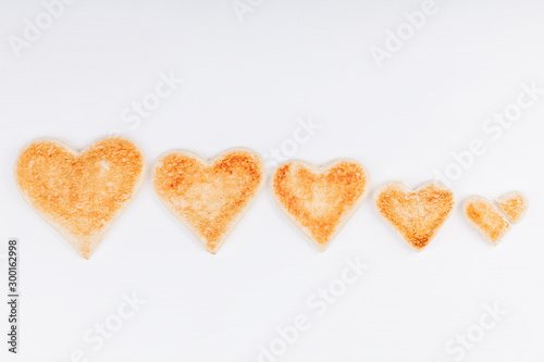 Group of toasted bread hearts with one broken heart together on white background. The concept of unhappy and misunderstanding in big family.
