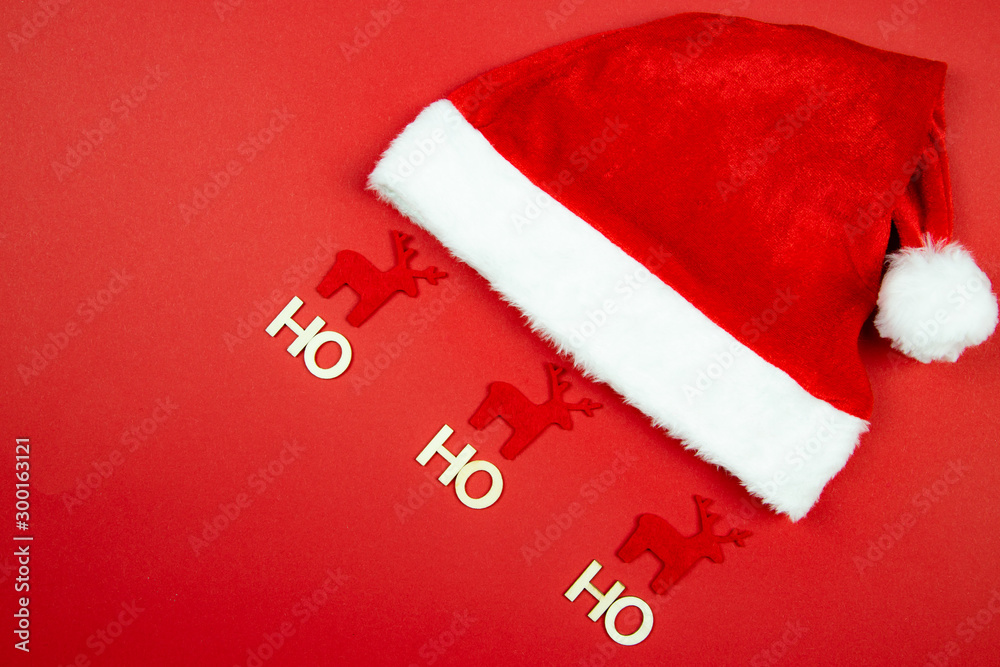 Święty Mikołaj i czapka wraz z reniferami na czerwonym tle - obrazy, fototapety, plakaty 