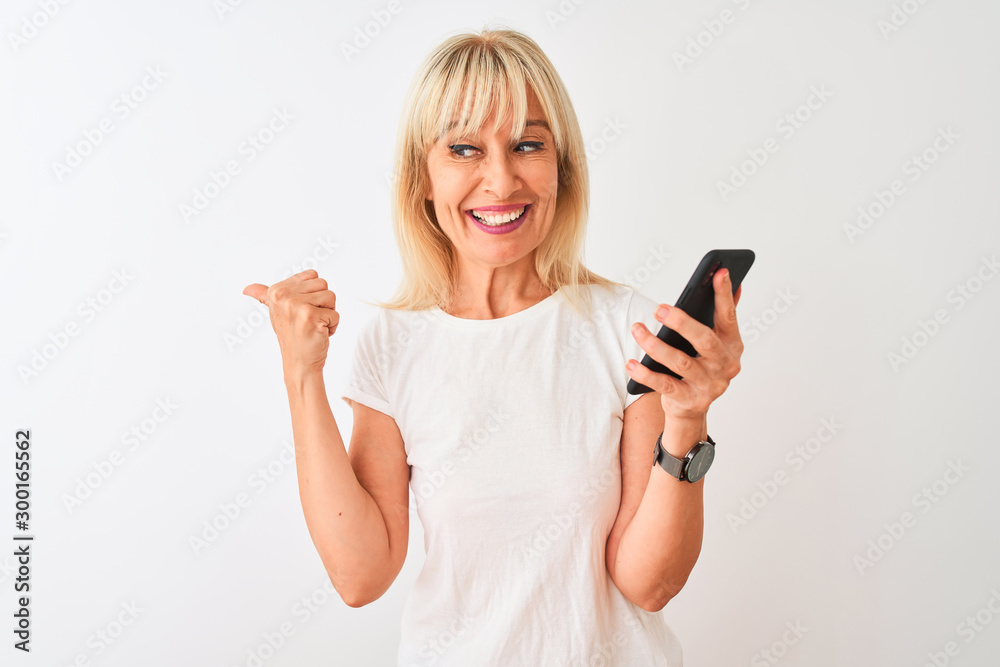 Middle age woman using smartphone standing over isolated white background pointing and showing with thumb up to the side with happy face smiling Middle age woman using smartphone standing over isolated white background pointing and showing with thumb up to the side with happy face smiling