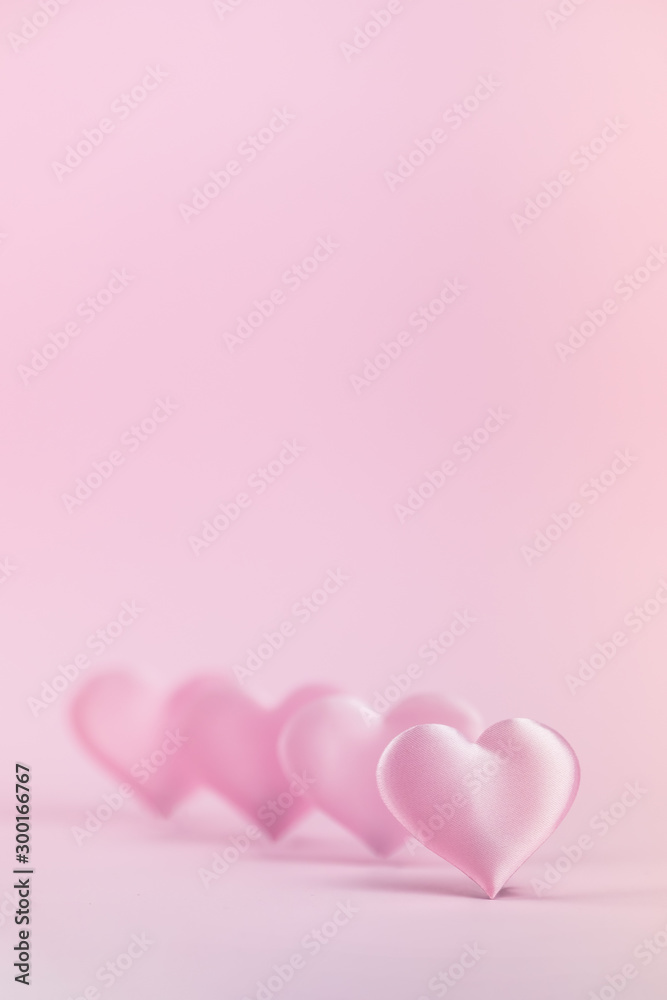 Pink silk heart on a pink background is standing in line. The concept of minimalism. Place for text. Pastel colors .