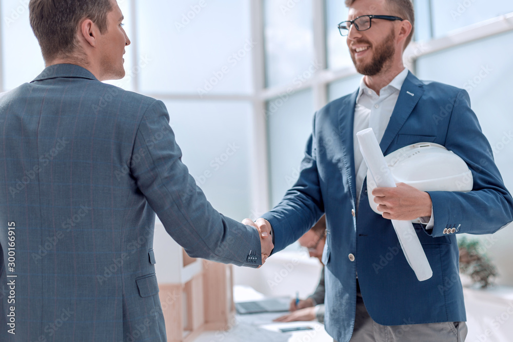 handshake contractor and architect on the background of the office. handshake contractor and architect on the background of the office.