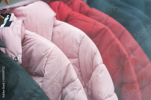 Closeup of colorful winter jackets on hangers in fashion store showroom