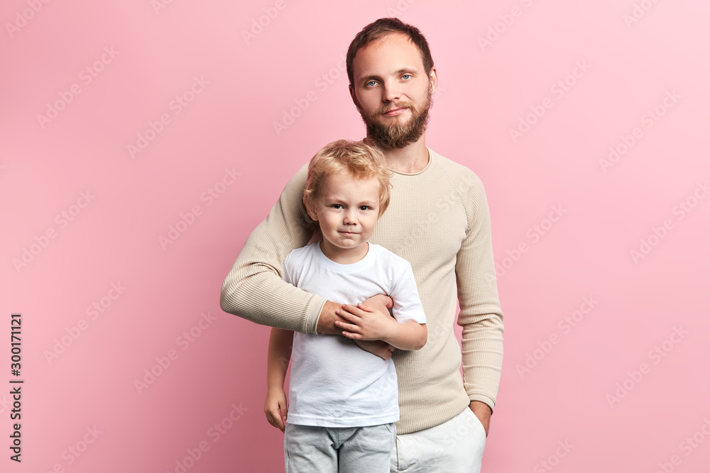 father and son looking at the camera while standing , happy fatherhood, parenthood. isolated pink background father and son looking at the camera while standing , happy fatherhood, parenthood. isolated pink background