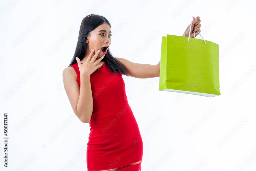 Young beautiful asian woman is surprised holding a shopping bag isolated on white background Young beautiful asian woman is surprised holding a shopping bag isolated on white background