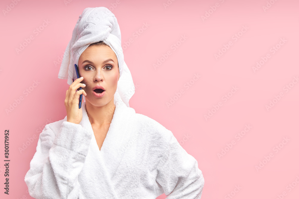 Young girl in towel standing isolated over pink background. Have conversation by smartphone. Young girl in towel standing isolated over pink background. Have conversation by smartphone.