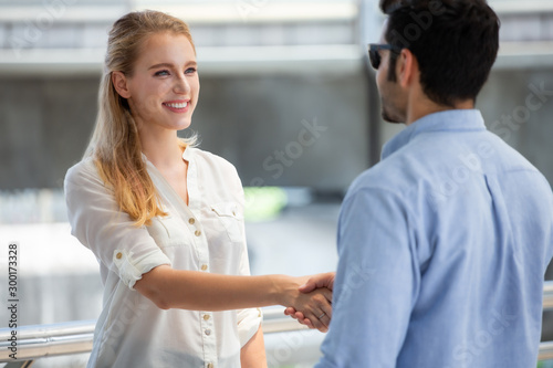 businesswoman shaking hands with businessman in urban city outdoors. introduce or welcome. greet. beautiful girl discussion with client. thanks gesture. entrepreneur agreement deal with customer