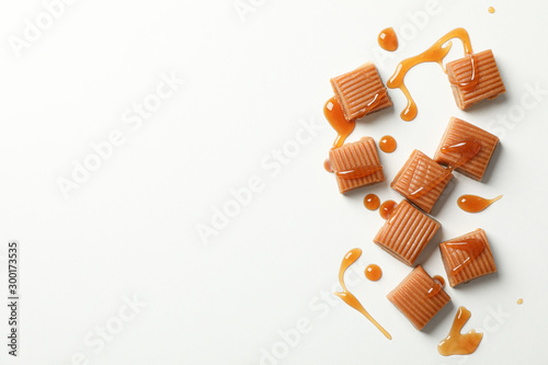 Salted caramel candies and sauce on white background, space for text photo