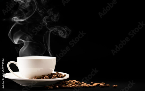 Cup coffee with steam and beans on a black background, a place for text.