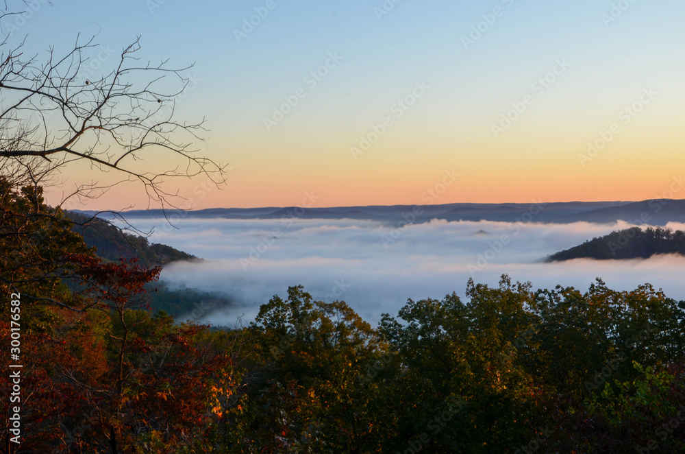 Obraz premium Early morning fog blankets the valley below. On a sunrise fall morning.