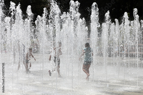 Fototapeta Naklejka Na Ścianę i Meble -  Happy children playing happily in the city fountain on a hot summer day.