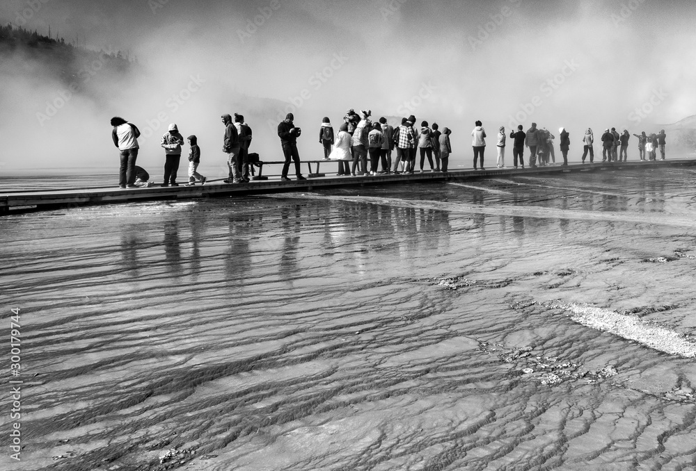 A crowd on wooden walk way over steam in black and white