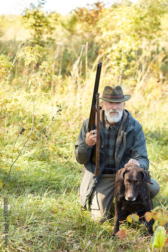 Senior hunter and his dog in forest, look for prey, hunting on wild animals. Hunting season