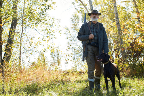 Senior hunter man with his dog in search of trophy, in forest © alfa27