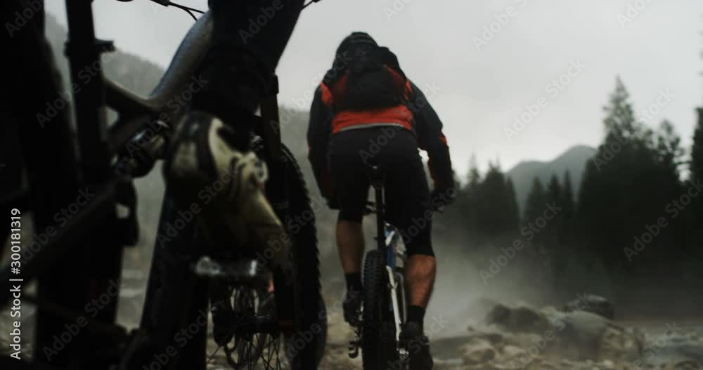 Mountain biker tower going over rocks with smoke in background slow motion