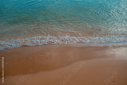 Waves crashing on the sand at the seashore with blue sea