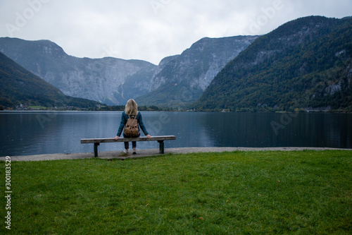 Young girl on a bench by a mountain lake enjoys the view