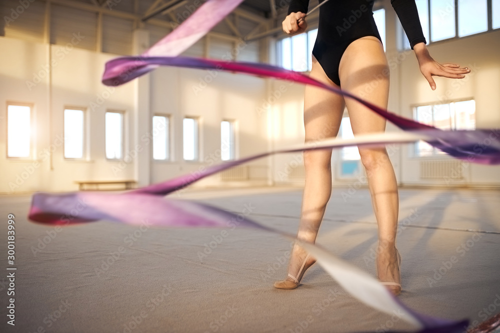 Close view of long legs of professional young gymnast training with violet ribbon in gymnstics school, active lifestyle concept Close view of long legs of professional young gymnast training with violet ribbon in gymnstics school, active lifestyle concept