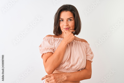 Young beautiful woman wearing casual t-shirt standing over isolated white background looking confident at the camera smiling with crossed arms and hand raised on chin. Thinking positive. © Krakenimages.com