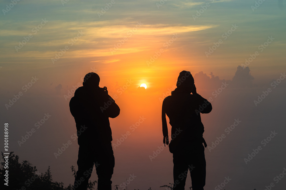 silhouette of a two man asian photographing the landscape during sunset
